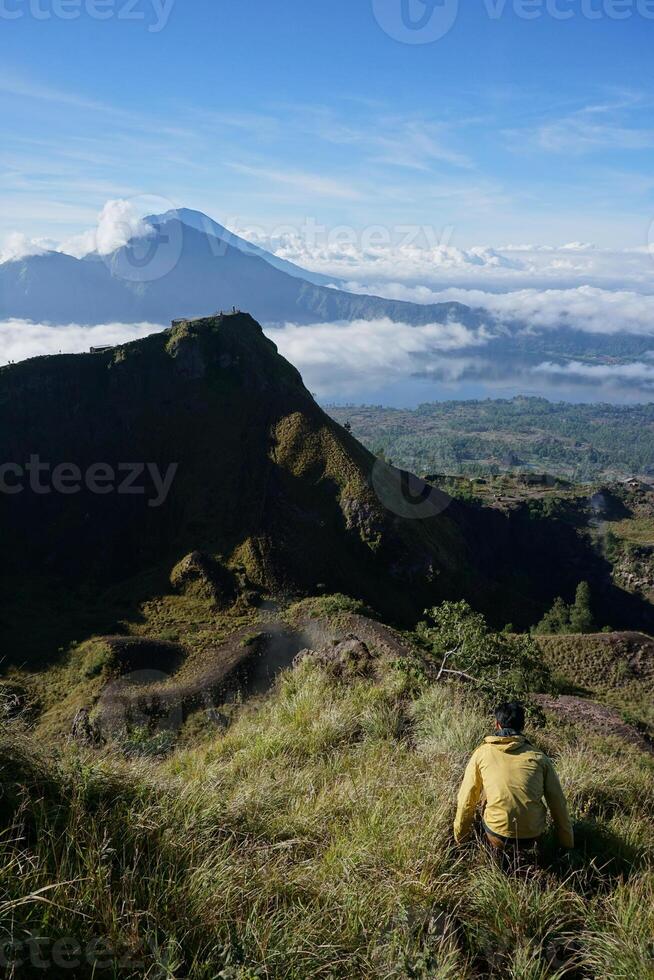 Above Cloud Nine, Mount Batur's Peak, Asian Man Trekker under Azure Sky and Cloud Sea photo