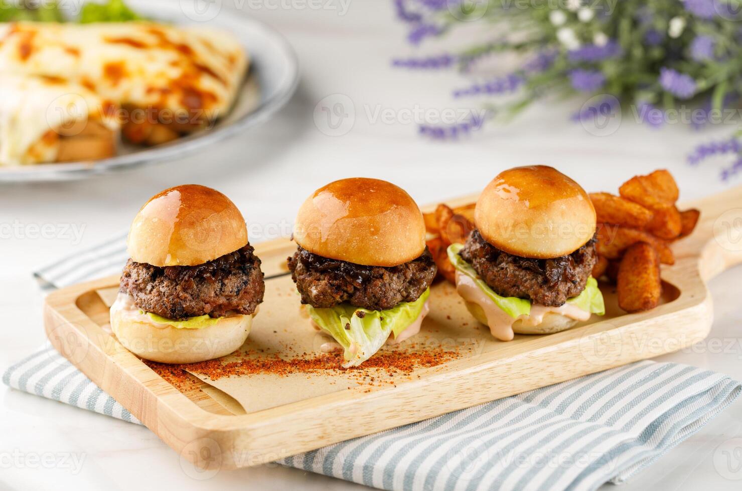 Three sandwiches with beef patties and wedges isolated on cutting board on table side view of arabian fastfood photo