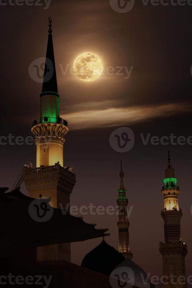 A mosque with the full moon in the sky. Masjid nabi of Medina, mosque at night. Masjid nabi of Medina. Green dome and moon.. photo