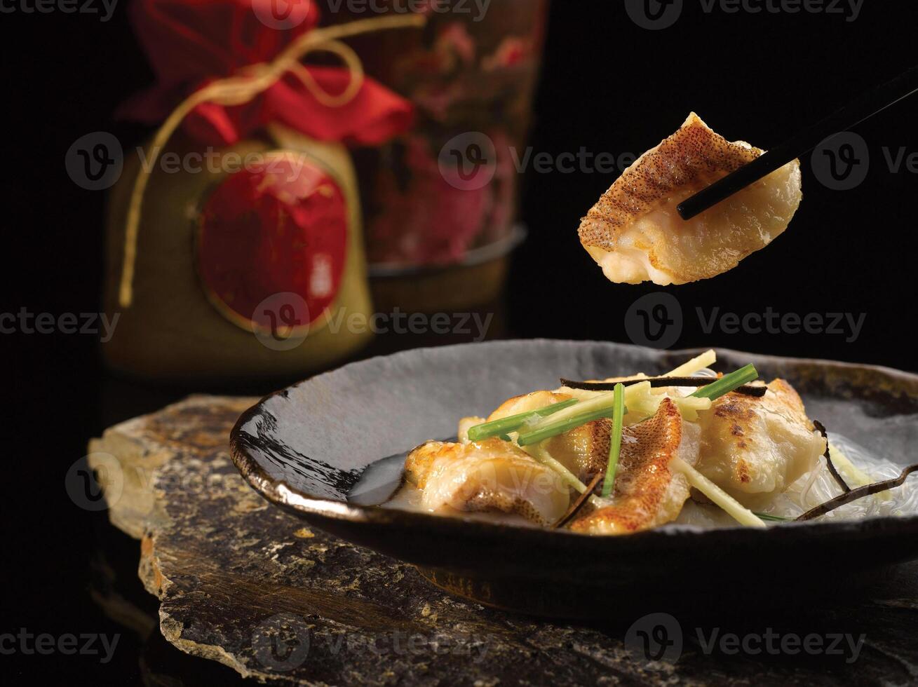 poached garoupa fish soup with ginger and chinese wine in superior broth isolated on background top view food photo