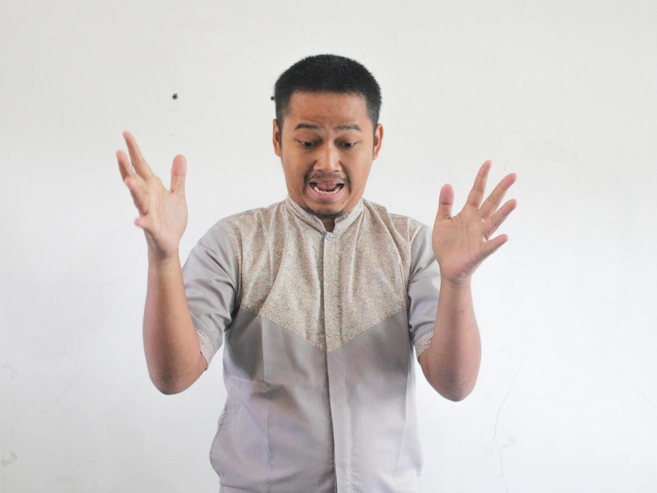 Adult Asian man showing shocked face expression when mobile phone fall from his hand photo
