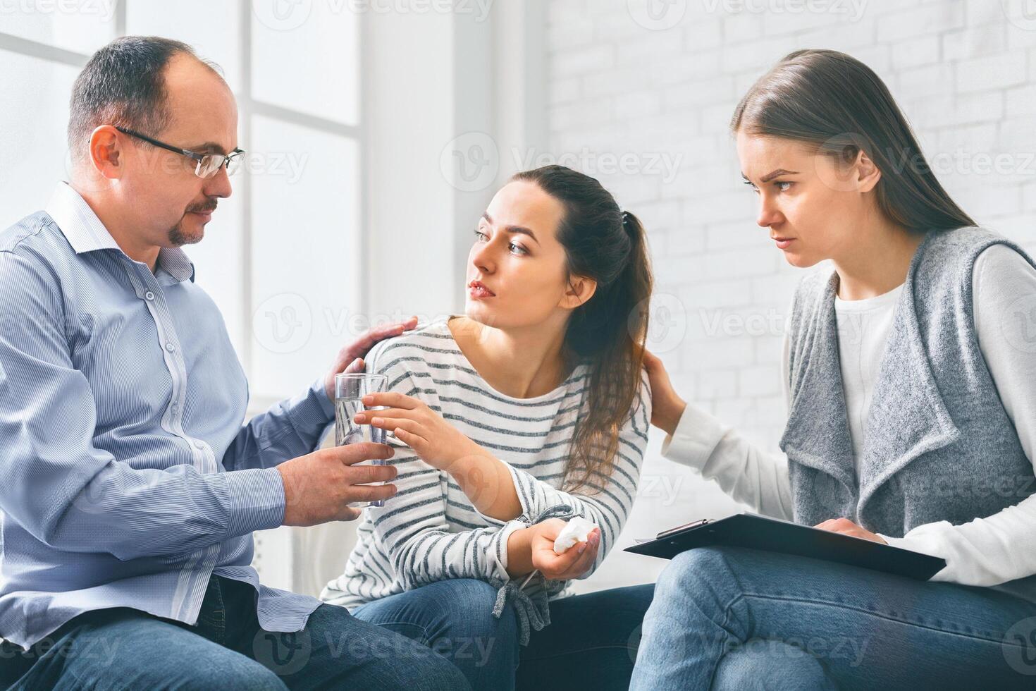 Concerned support group mebers comforting emotional young woman at therapy session photo