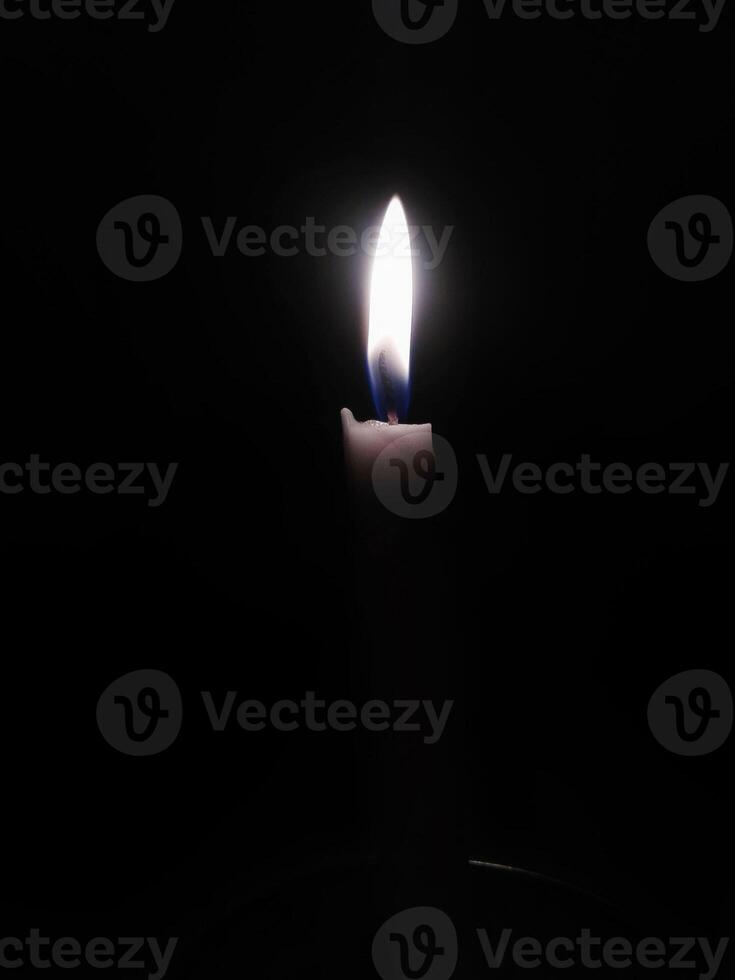 Candle on dark background.Burning candle flame closeup view.Light and dark contrast photo