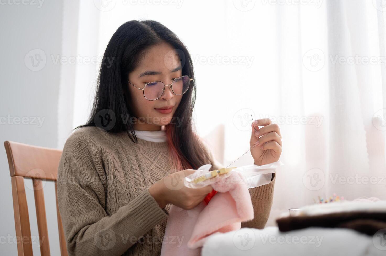 A beautiful Asian woman is focusing on hand-sewing a pattern on cloth on an embroidery frame. photo