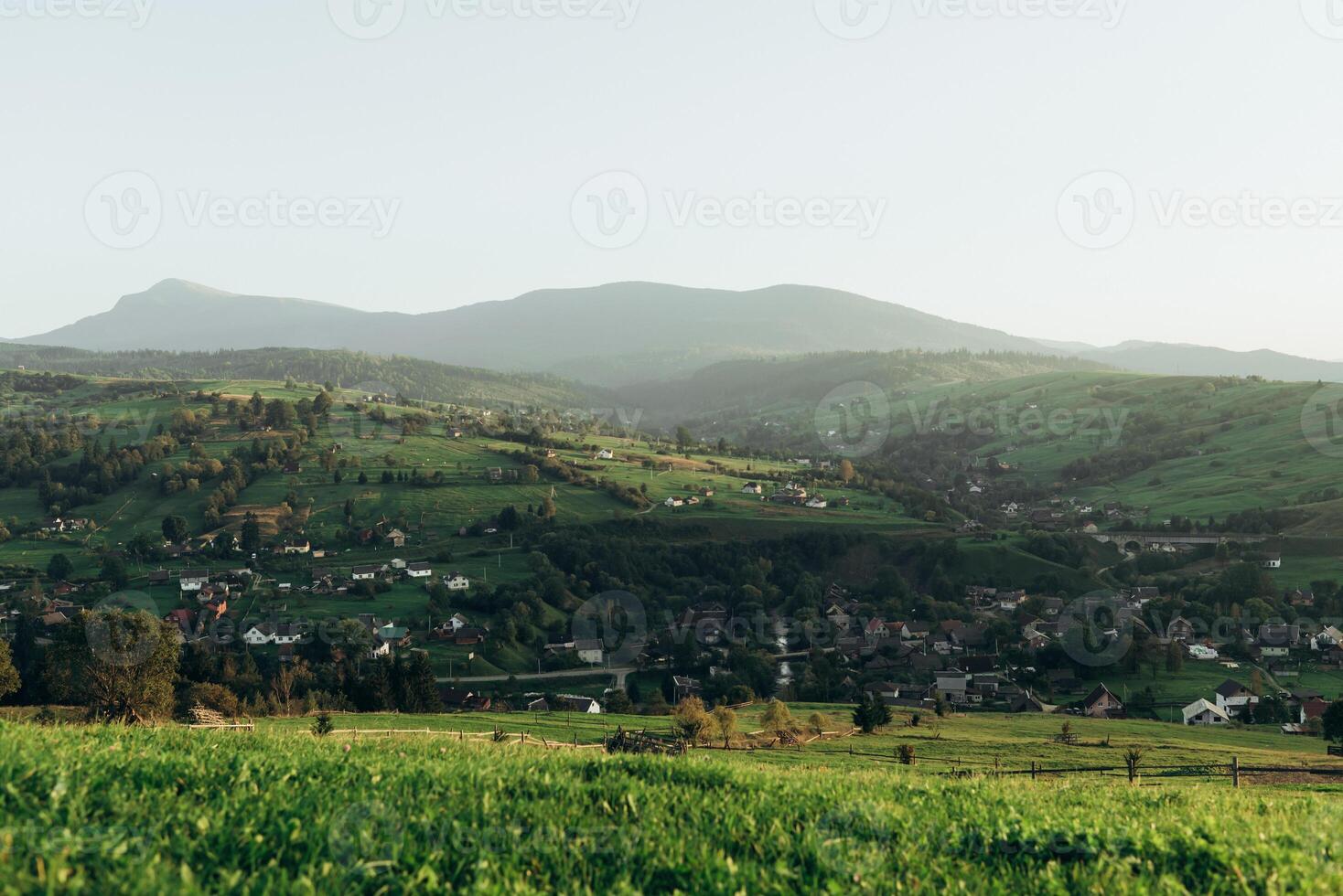 prado con verde césped y montañas con pueblo ver yasinya, zakarpatia foto