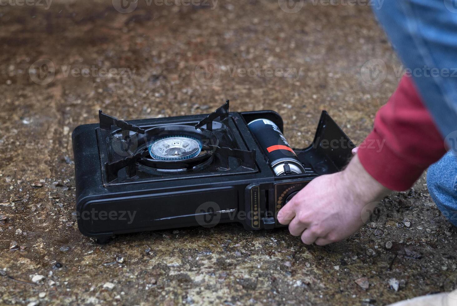 Active lifestyle. A man's hand turns on a portable gas stove. An alternative source for cooking at home during a power outage. photo