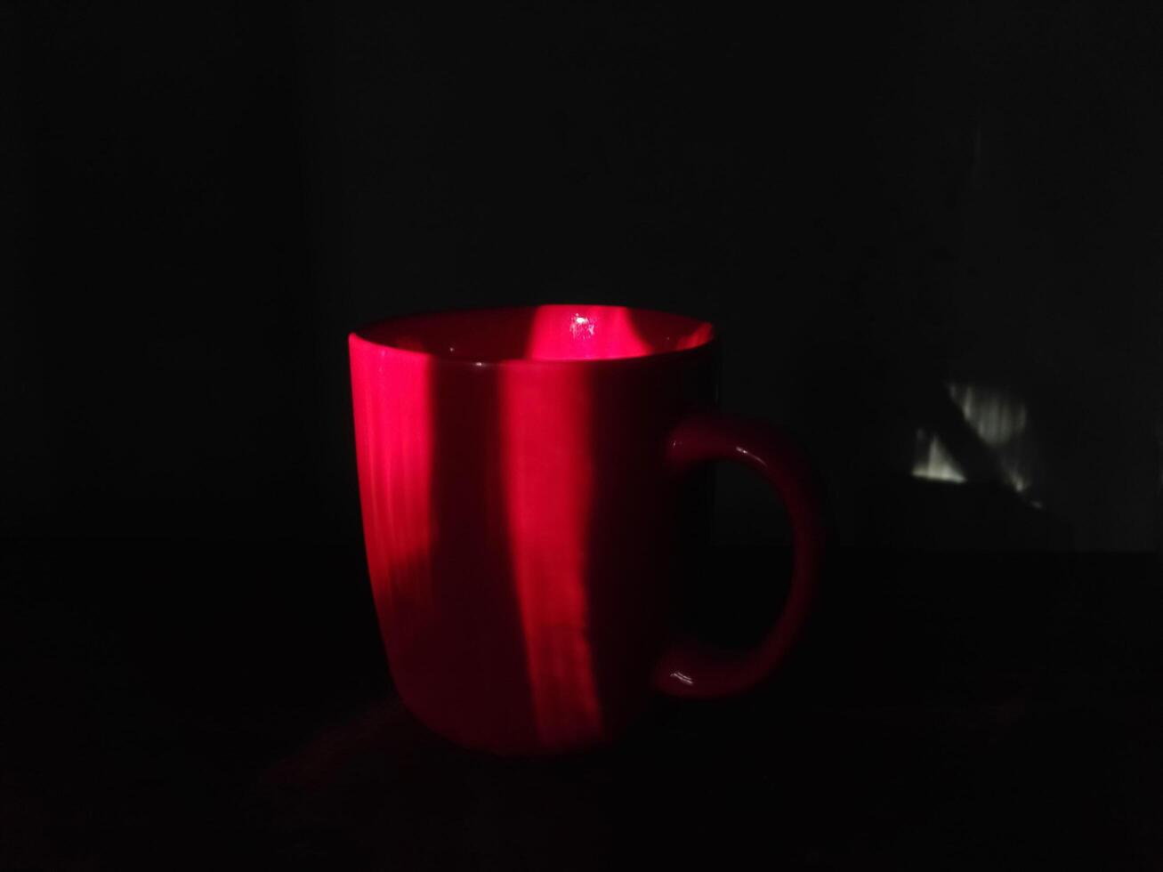 Red coffee mug on dark background.Red,black contrast photo