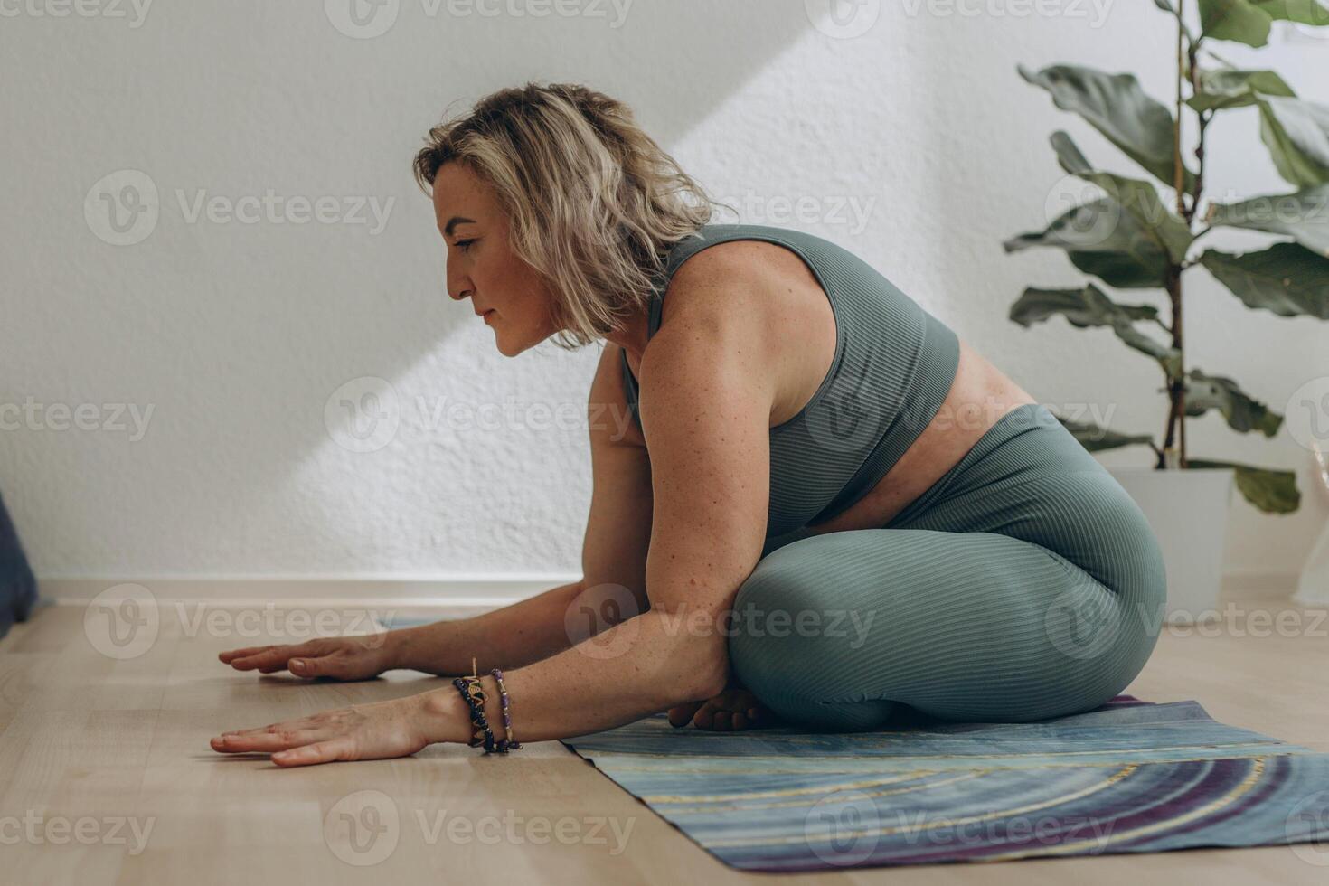 A 50-year-old woman does yoga at home photo