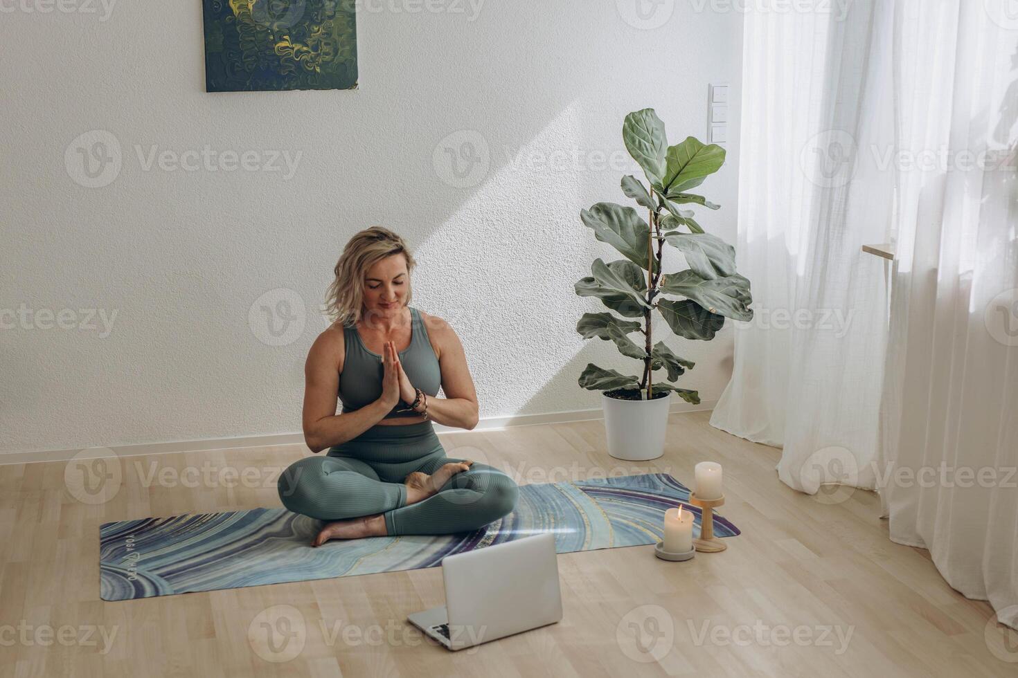 A 50-year-old woman doing online yoga at home photo