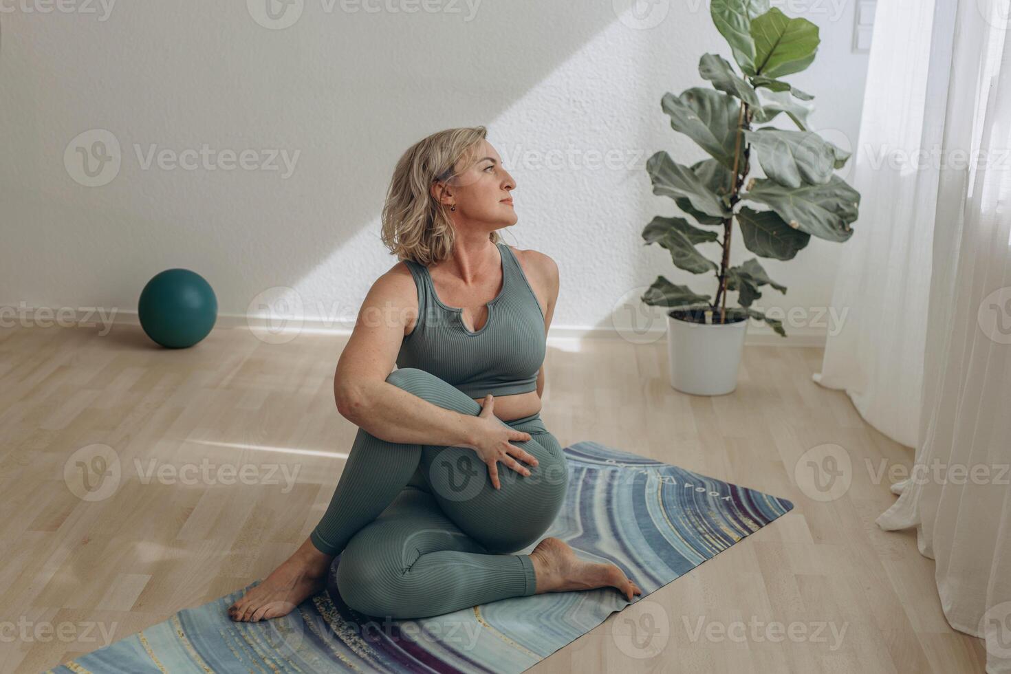 A 50-year-old woman does yoga at home photo