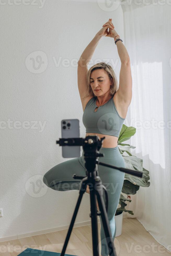 A 50-year-old woman doing online yoga at home photo