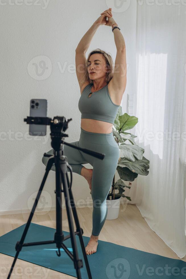 A 50-year-old woman doing online yoga at home photo