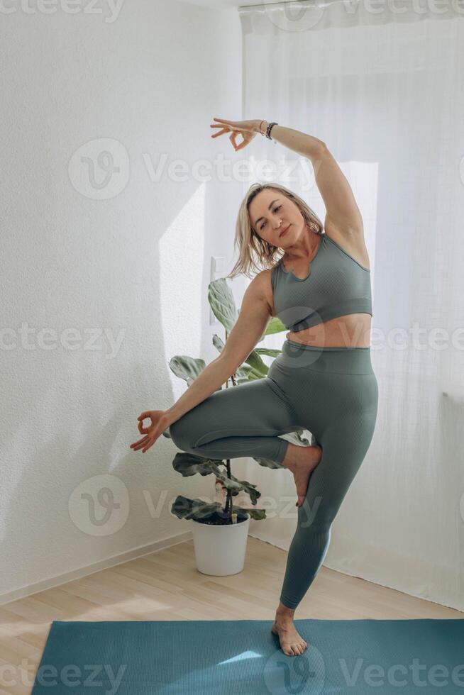 A 50-year-old woman does yoga at home photo