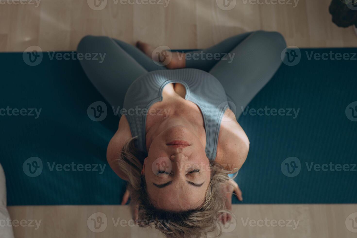 A 50-year-old woman does yoga at home photo