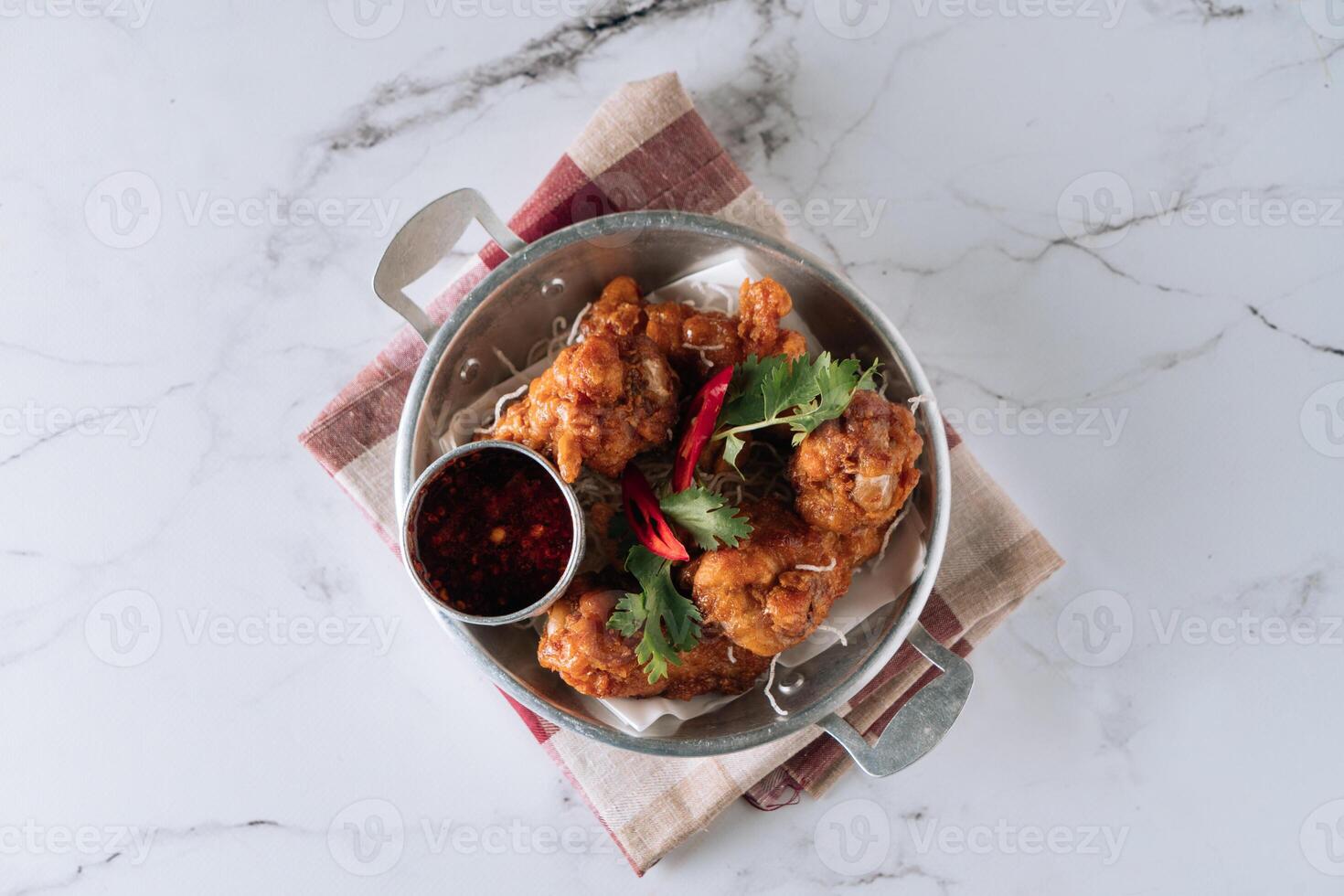 Korean fried chicken drumlets with chili sauce in a dish isolated on mat top view on grey marble background photo