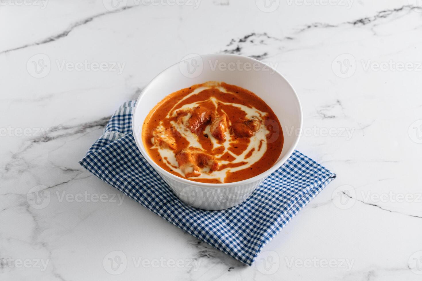 Traditional indian food Murgh Makhani or Butter chicken, tikka masala in a dish isolated on napkin side view on grey background photo