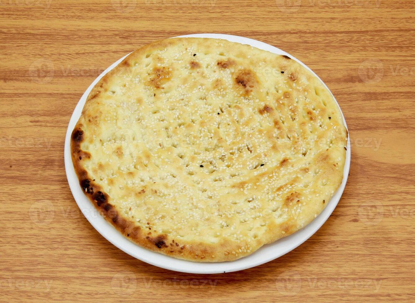 Roghni naan or nan, nun, roti, tandoori, chapati, pita, bread served in a dish isolated on wooden table side view of indian, pakistani food photo