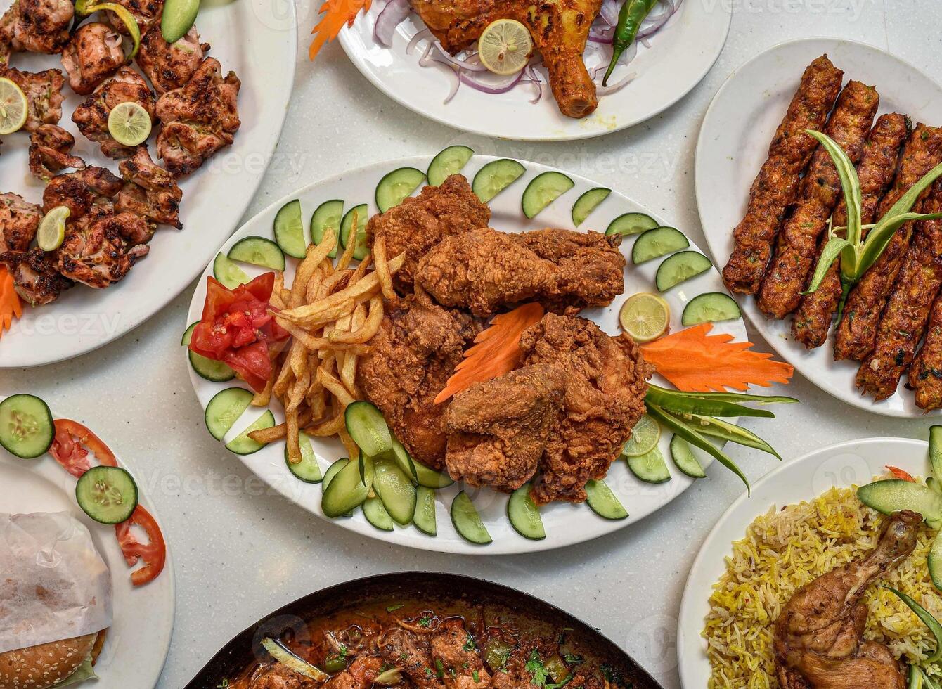 chicken steam roast, biryani, tikka boti, seekh kabas, burger, salad and fries served in a dish isolated on grey background top view of indian, pakistani food photo