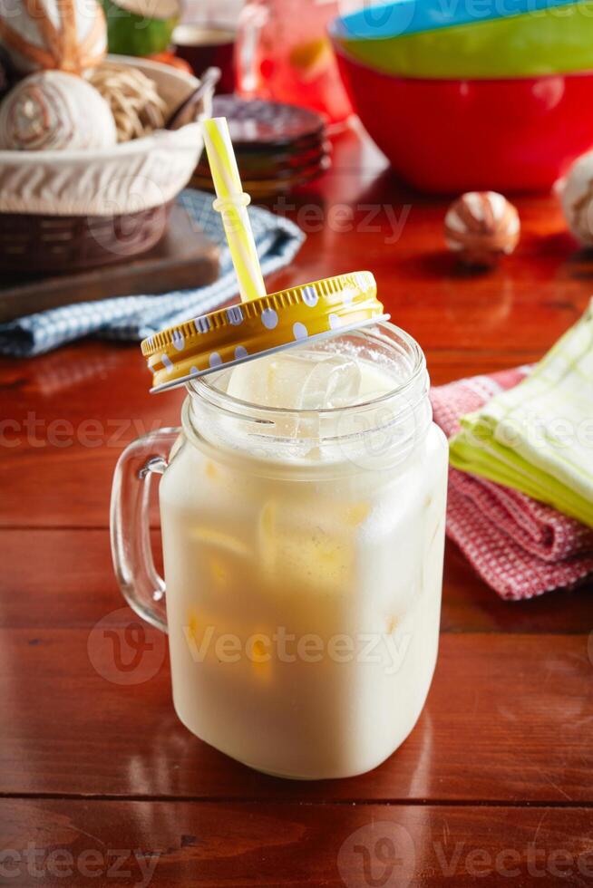 A jar of healthy fresh PINE COLADA with straw isolated on wooden background side view photo