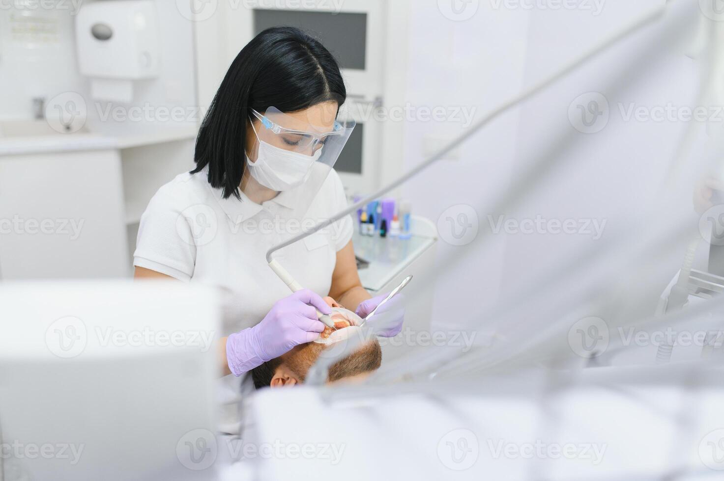 hombre teniendo un visitar a el del dentista. hermoso paciente sentado en silla a dentista oficina en dental clínica. foto