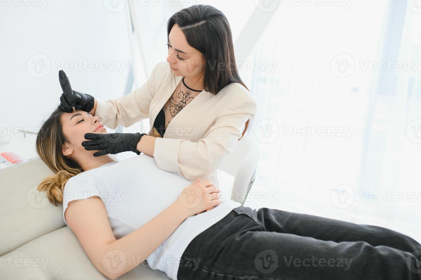 Cosmetologist applying permanent make up on eyebrows- eyebrow tattoo photo