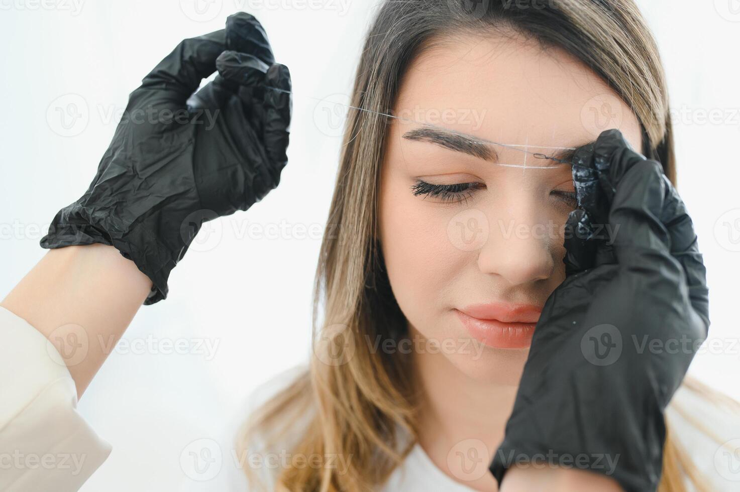 Cosmetologist applying permanent make up on eyebrows- eyebrow tattoo photo