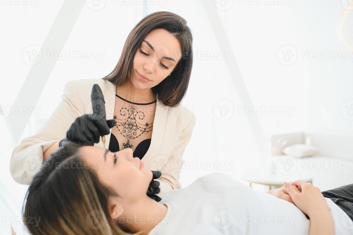 Cosmetologist applying permanent make up on eyebrows- eyebrow tattoo photo