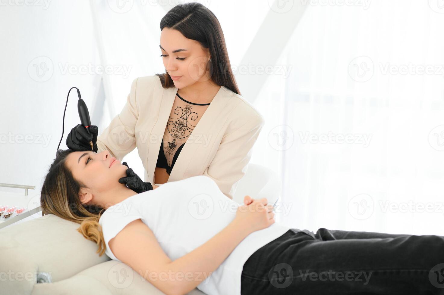 Cosmetologist applying permanent make up on eyebrows- eyebrow tattoo photo