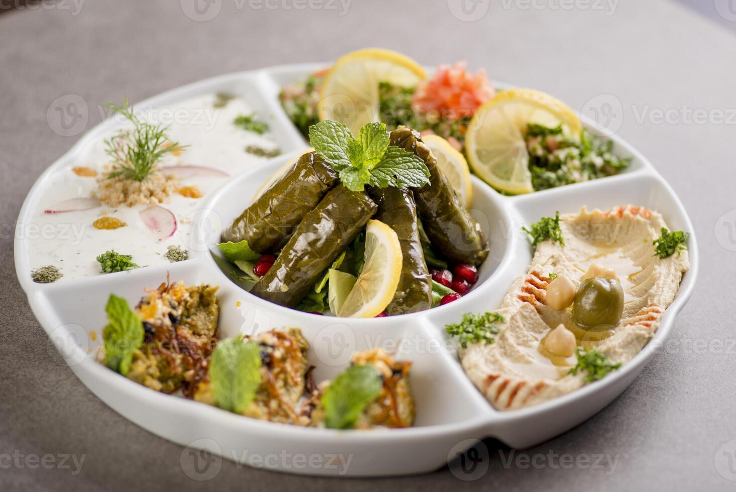 arabian mix starter with vine leaves, hummus, mezze, fatoush served in dish isolated on grey background top view of arabic food photo