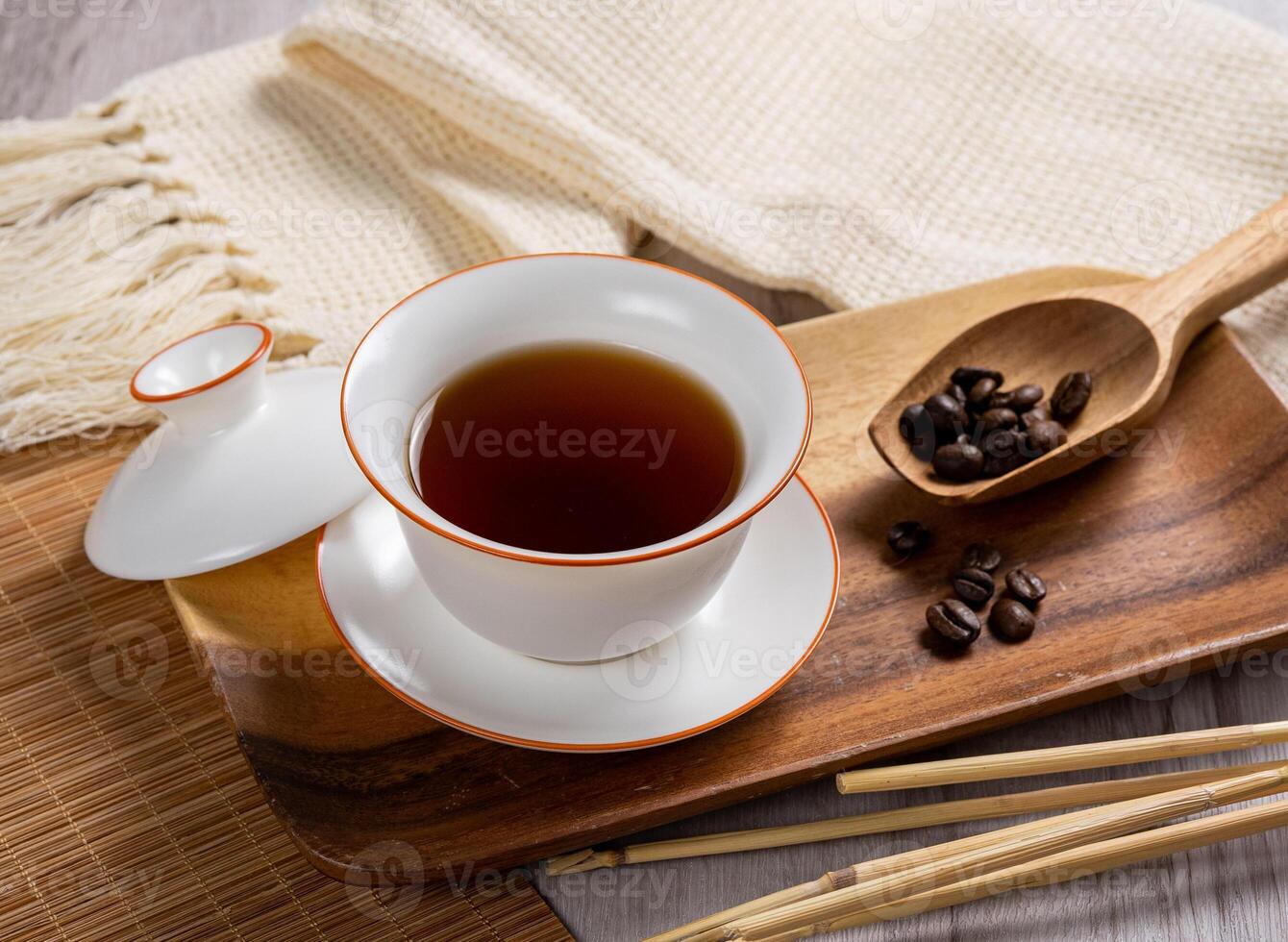 Cup of coldbrew coffee with iced and raw coffee beans on wooden spoon on dish photo