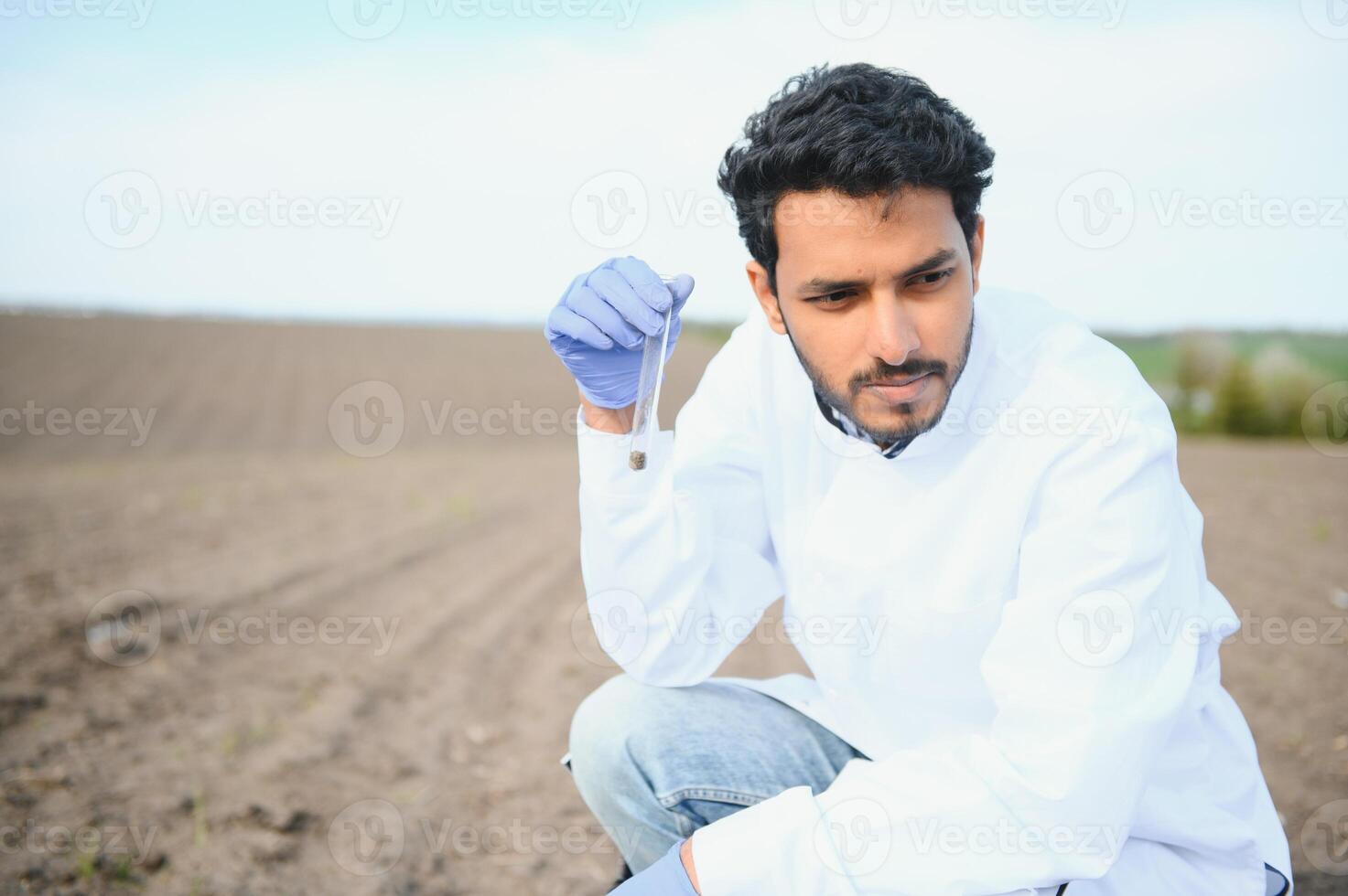 Soil Testing. Indian Agronomy Specialist taking soil sample for fertility analysis. Hands in gloves close up. Environmental protection, organic soil certification, field work, research photo