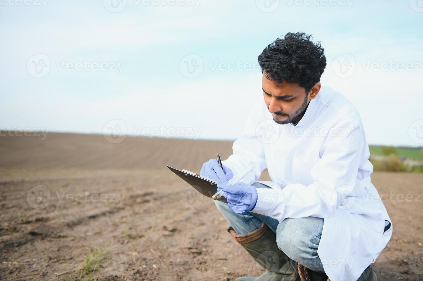 suelo prueba. indio agrónomo poniendo suelo con jardín pala en suelo muestra bolso exterior. ambiental investigación foto