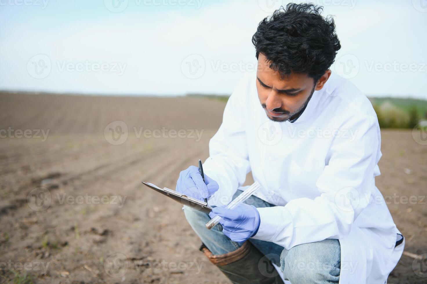 suelo prueba. indio agrónomo poniendo suelo con jardín pala en suelo muestra bolso exterior. ambiental investigación foto