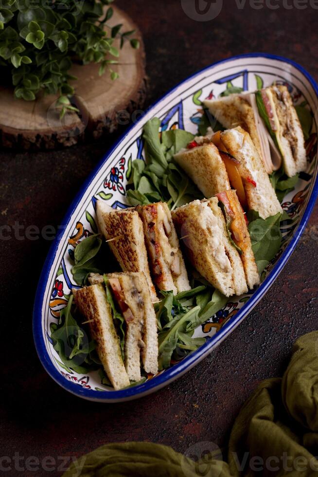 Assorted club sandwiches served in a tray isolated n wooden table top view photo