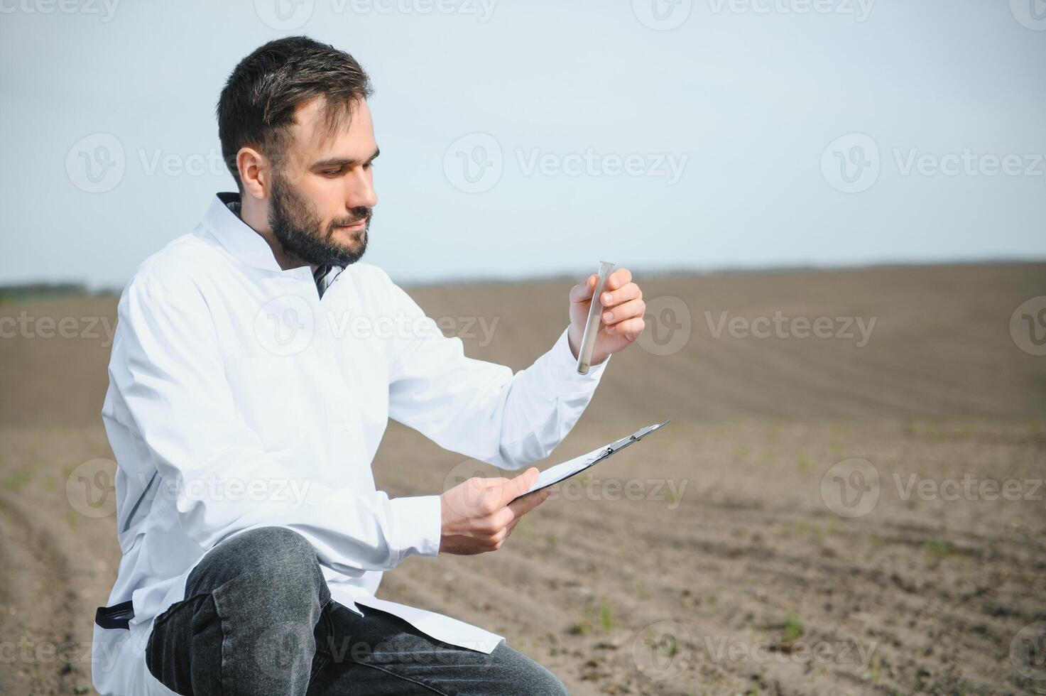 Agronomist studying samples of soil in field photo
