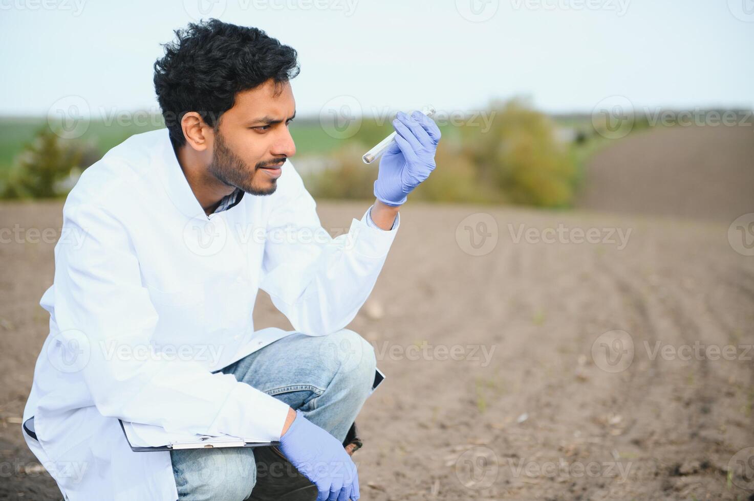 suelo prueba. indio agrónomo poniendo suelo con jardín pala en suelo muestra bolso exterior. ambiental investigación foto