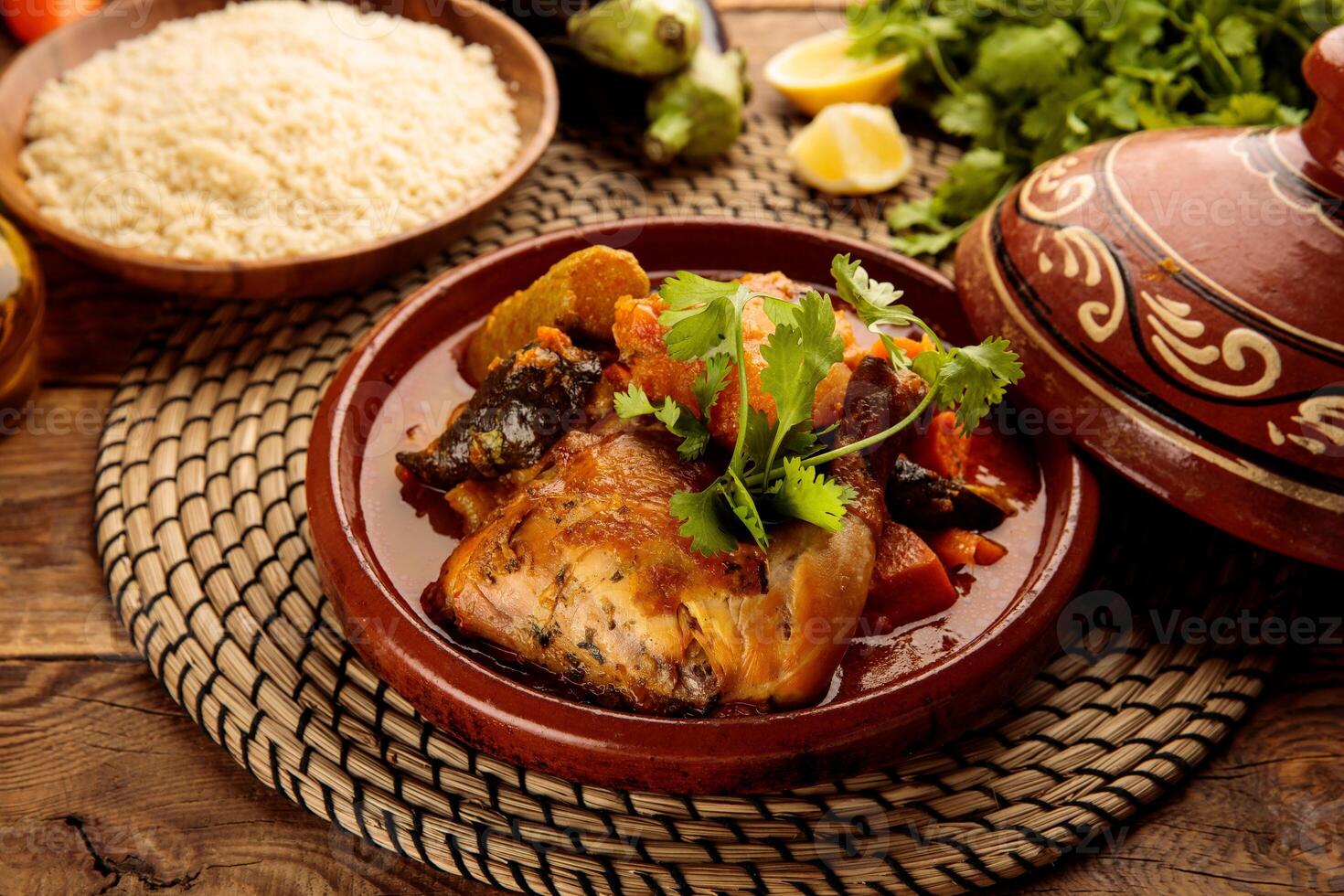 Moroccan Chicken and Vegetables Tangine with Couscous and bread served in a dish isolated on wooden background side view photo