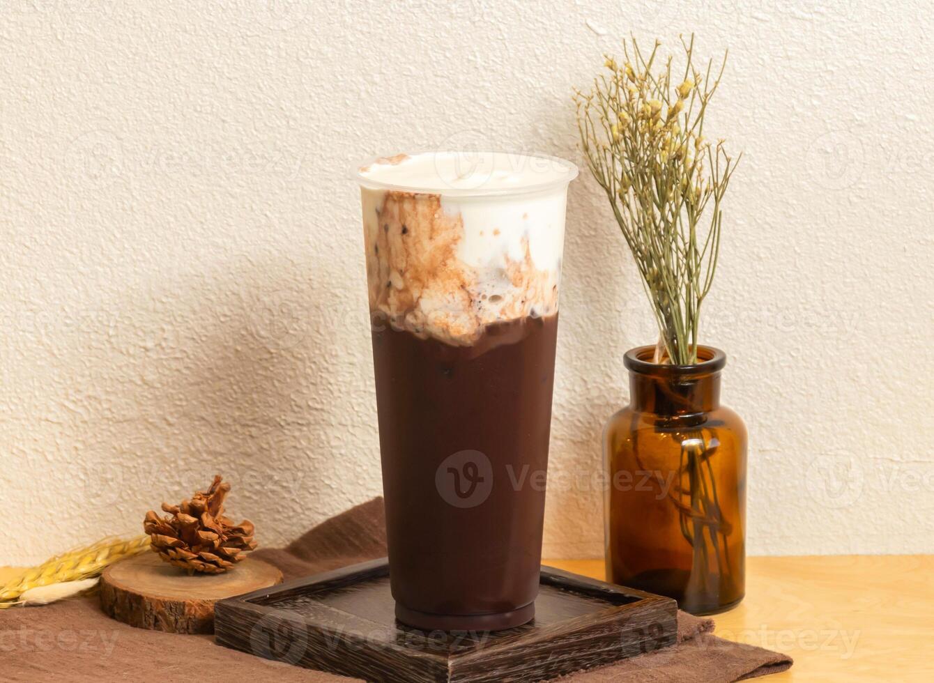 Iced Valrhona cocoa milk tea served in disposable glass isolated on wooden board side view of taiwanese ice drink photo