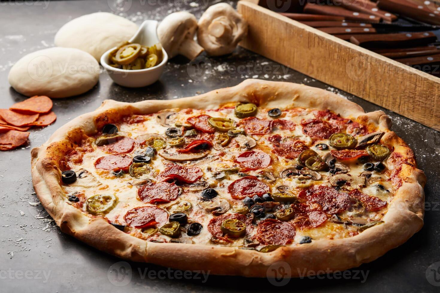 Flamin Pizza topping with mushroom, pepperoni and olive isolated on dark background with raw food top view of italian fastfood appetizer photo