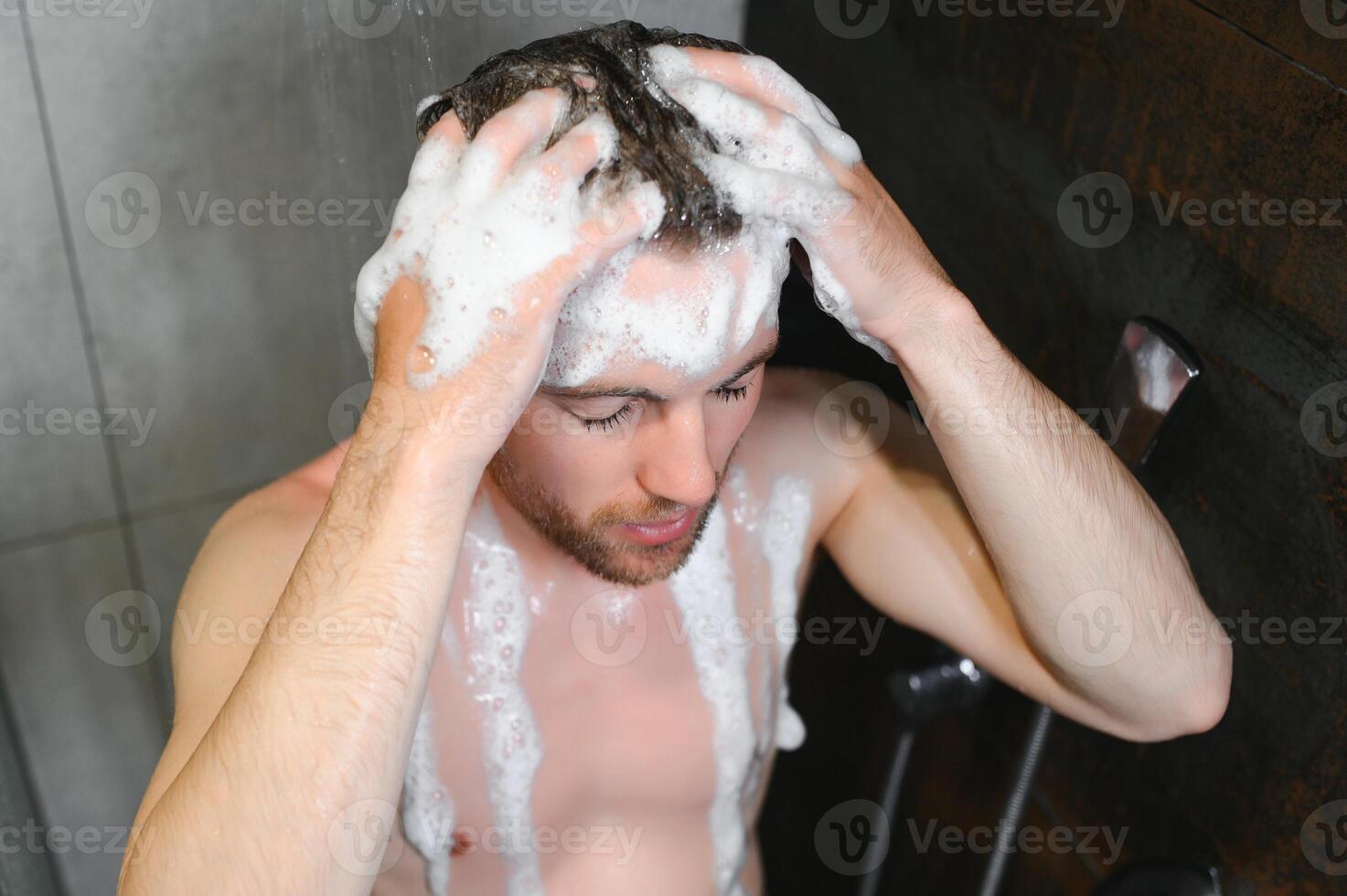 Handsoome man taking shower in modern bathroom photo