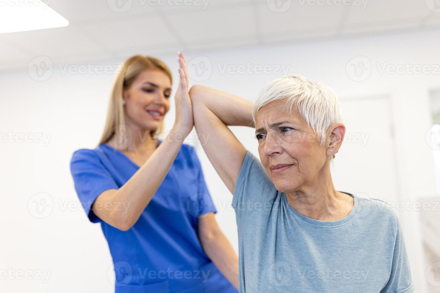 Doctor orthopedic teaching senior woman to do osteoporosis treatment exercise in modern clinic. Physiotherapist helping female patient during muscle rehabilitation physiotherapy photo