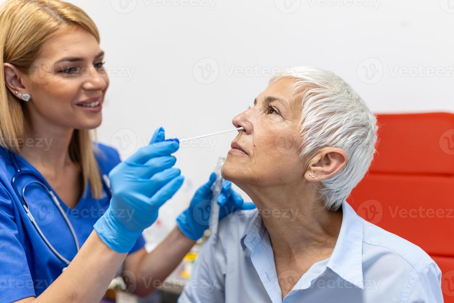 Female patient being tested for Covid-19 with a nasal swab, by a health Professional protected with gloves and PPE suit. Rapid Antigen Test during Coronavirus Pandemic. photo