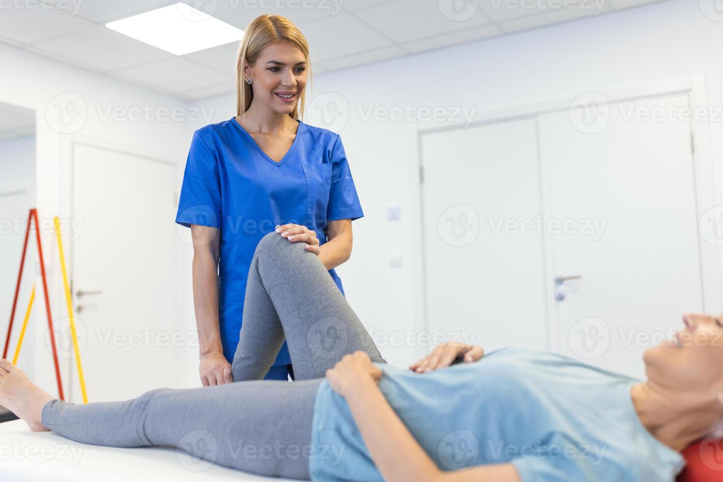 Physiotherapist working with patient in clinic, closeup. A Modern rehabilitation physiotherapy worker with senior client, Physical therapist stretching patient knee photo