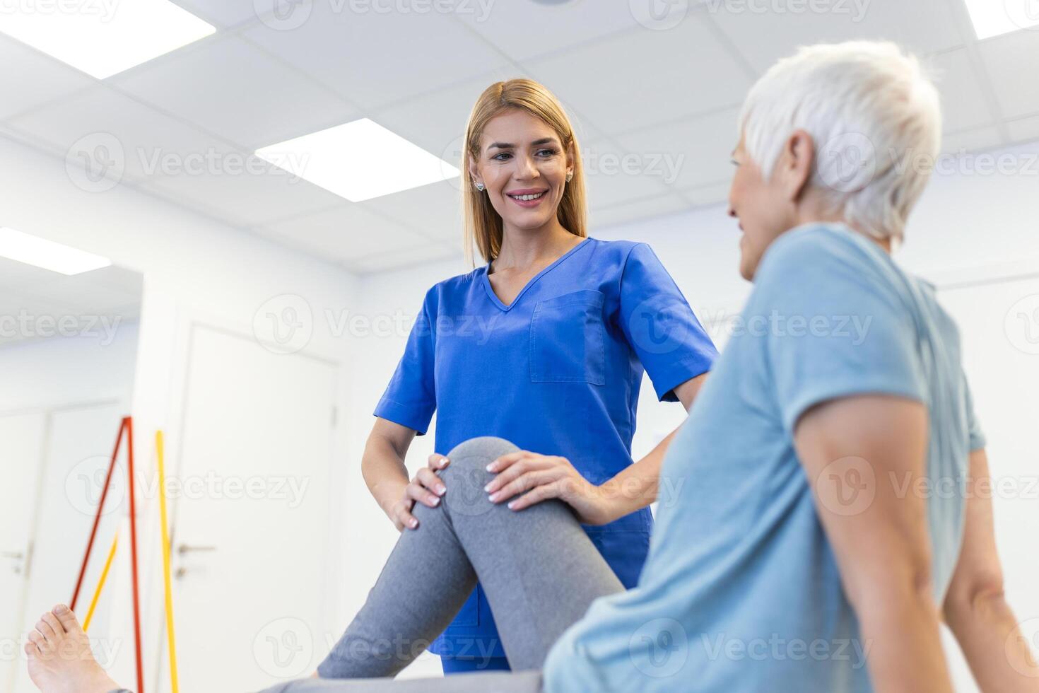 fisioterapeuta trabajando con paciente en clínica, de cerca. un moderno rehabilitación fisioterapia trabajador con mayor cliente, físico terapeuta extensión paciente rodilla foto