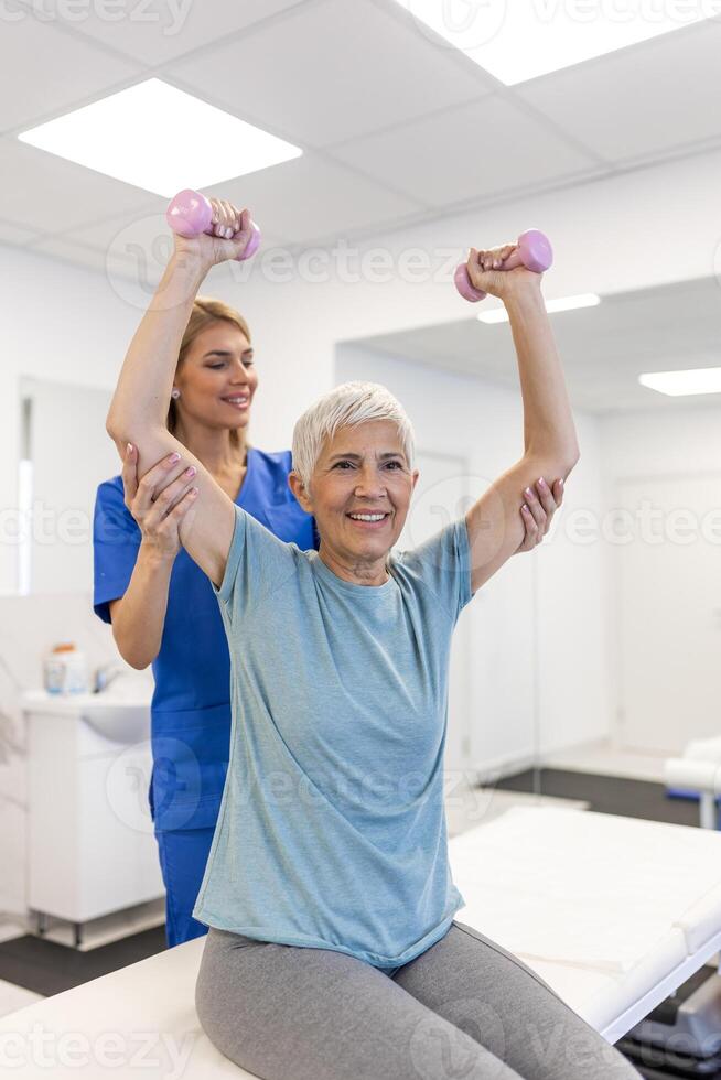 oder Envejecido mujer haciendo fisioterapia con apoyo desde fisioterapeutas . mayor mayor hembra sentado en clínica utilizando pesas rutina de ejercicio ejercicio para paciente con cuidador en enfermería cuidado. foto