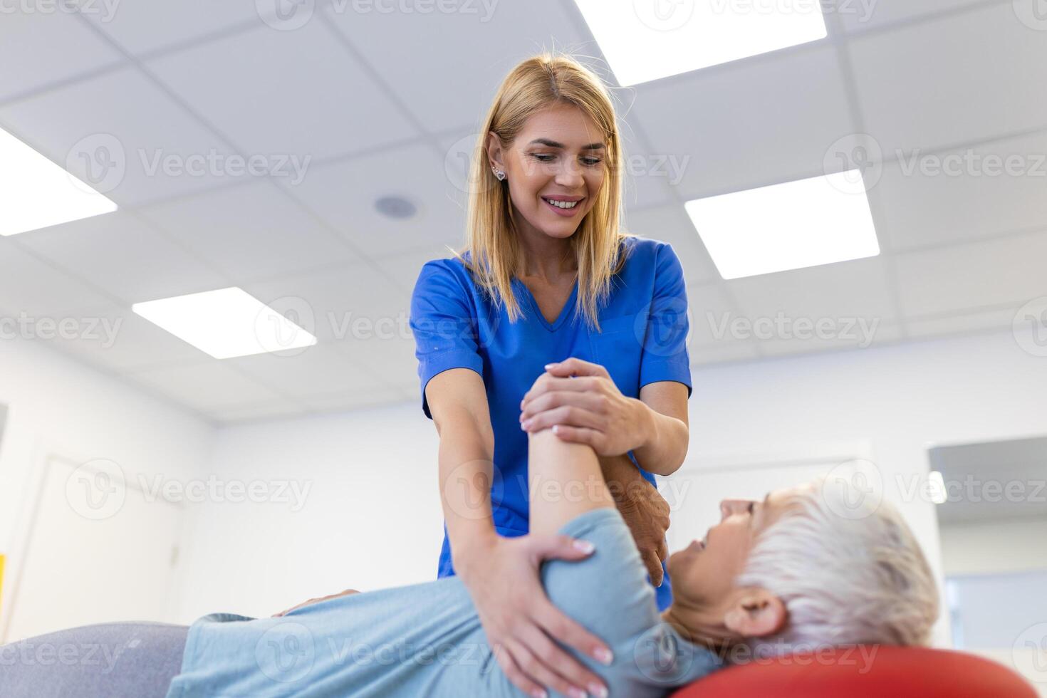 Doctor or physiotherapist helps to heal a senior woman's back. and give advice within the rehabilitation center. Concept of physical rehabilitation. photo