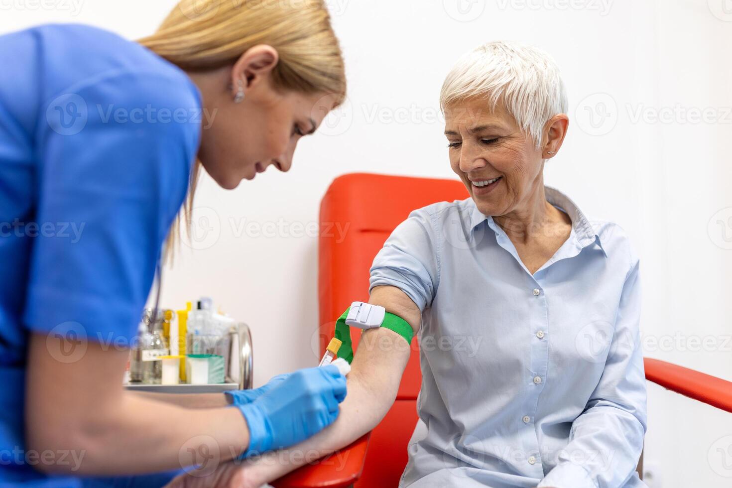 Medical technologist doing a blood draw services for patient. lab assistant with sterile rubber gloves taking blood sample from patient. photo