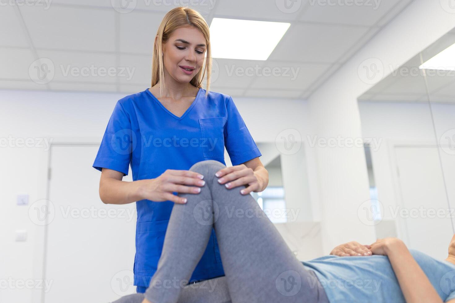 Senior patient at the physiotherapy doing physical exercises with her therapist, doing leg physiotherapy for elderly woman, to treat osteoarthritis and nerve pain in the leg. photo