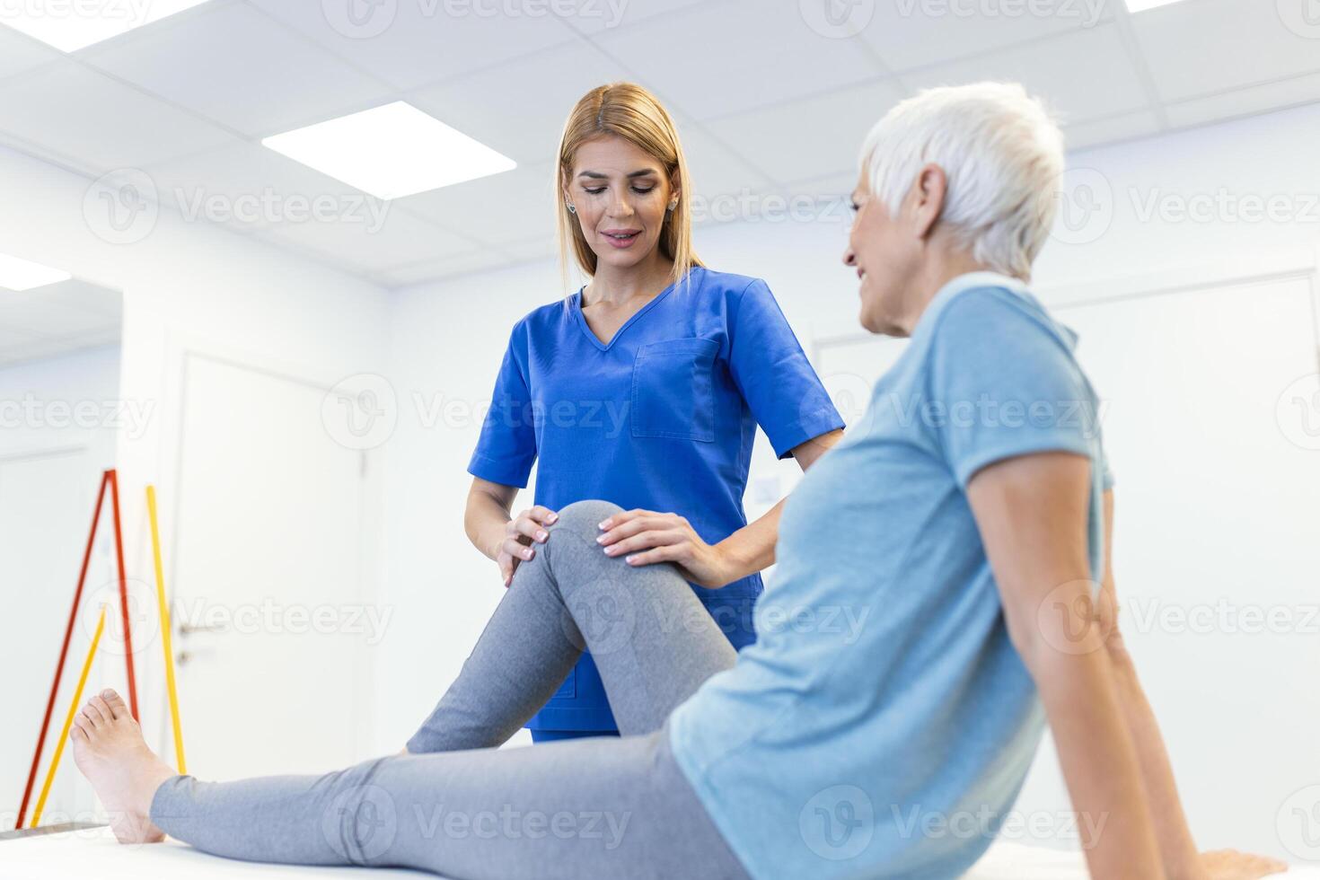 fisioterapeuta trabajando con paciente en clínica, de cerca. un moderno rehabilitación fisioterapia trabajador con mayor cliente, físico terapeuta extensión paciente rodilla foto