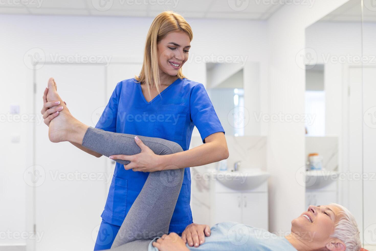 Senior patient at the physiotherapy doing physical exercises with her therapist, doing leg physiotherapy for elderly woman, to treat osteoarthritis and nerve pain in the leg. photo